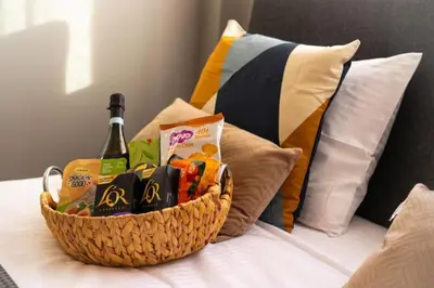 a basket of food and a bottle of wine on a bed at Stylish Newly Renovated Flat, 250 Meters from the Beach, Central Location with Free Parking in Limassol