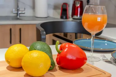 a cutting board with fruits and vegetables and a glass of juice at Beautiful One Bedroom Apartment, 186 Meters to Beach, Central Location Next to Cafes & Bars in Limassol