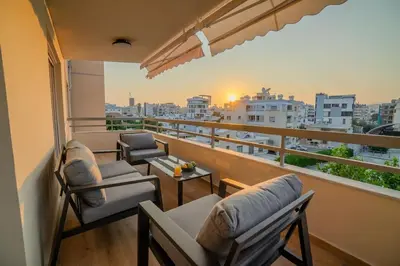 a balcony with chairs and tables and a view of a city at Two Bedroom Apartment, Spacious & Newly Renovated, Three Minutes from the Beach in Limassol