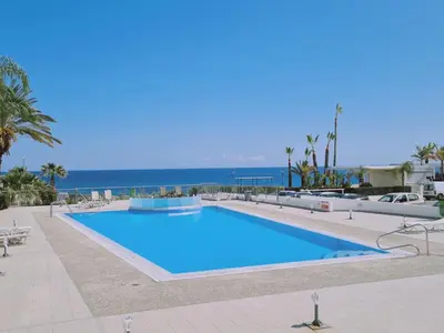a large swimming pool with the ocean in the background at Coralli Privileges Apt in Protaras