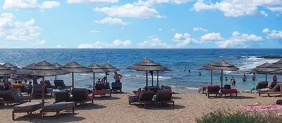 a beach with people sitting in chairs and umbrellas at Soleil Residence - Charming 2BR Holiday House with Garden at Protaras - Konnos Area in Protaras