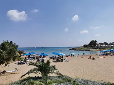 a beach with a lot of people and blue umbrellas at Relax by the sea in Protaras