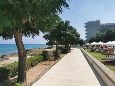 a sidewalk next to the beach with people sitting at Relax by the sea in Protaras