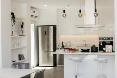 a kitchen with white cabinets and a stainless steel refrigerator at Protaras Bay View Villa 11 in Protaras