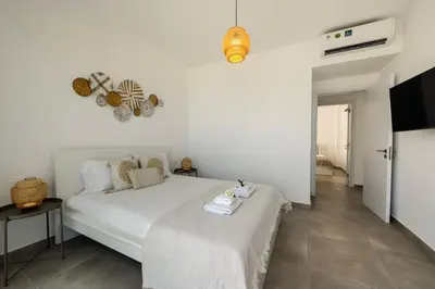 a white bedroom with a bed and a television at Protaras Bay View Villa 11 in Protaras