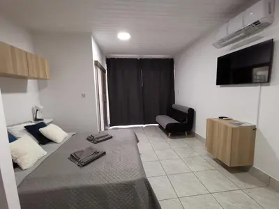 a room with a bed and a chair and a television at Freminore Eden Studio in Ayia Napa