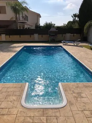a swimming pool with blue water in front of a house at Palm Villa 3 bedrooms - Sleeps 6 in Ayia Napa