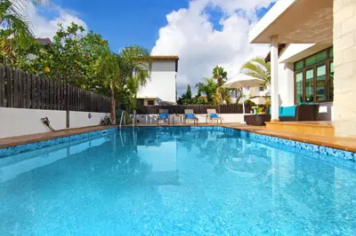 a swimming pool with blue water in front of a house at Villa Merry in Ayia Napa