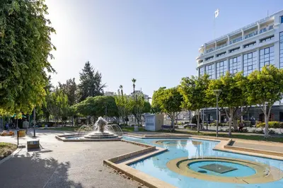 a fountain in a park in front of a building at 74 Prokymea- Steps from the Sea, Downtown, Balcony in Limassol