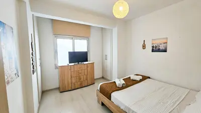 a bedroom with a bed and a flat screen tv at Seaside Comfort Residence in Larnaka