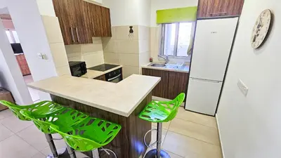 a kitchen with a counter and two green stools at Seaside Comfort Residence in Larnaka