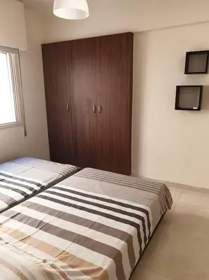 a bedroom with two beds and a wooden cabinet at Cozy comfortable 2-bedroom apartment in Limassol
