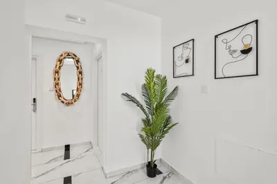 a white hallway with a plant and a mirror at Lazuli Hermes Apartments in Larnaka