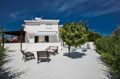 a patio with chairs and a tree in front of a house at Merab Center Villas in Ayia Napa