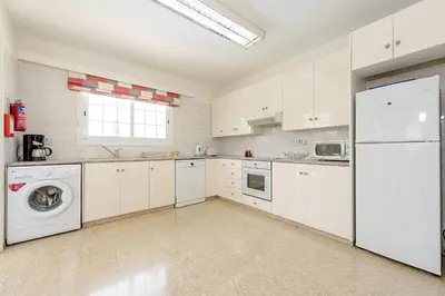 a kitchen with white cabinets and a washer and dryer at Merab Center Villas in Ayia Napa