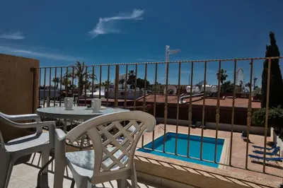 a balcony with a table and chairs and a pool at Napiana Apartments in Ayia Napa