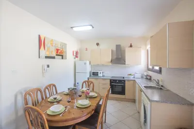 a kitchen with a wooden table and chairs and a kitchen with a sink at Napiana Apartments in Ayia Napa