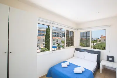 a bedroom with a bed and two windows at Delfini Villas in Protaras