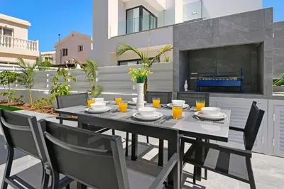 a dining table and chairs on a patio with a fireplace at Villa Flora - 3Bed all En-suite with Private Pool in Paralimni