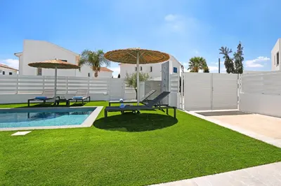a yard with a pool and two benches and umbrellas at Villa Flora - 3Bed all En-suite with Private Pool in Paralimni