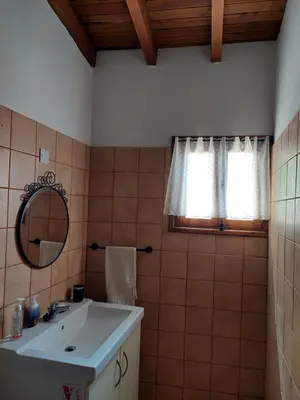 a bathroom with a sink and a mirror and a window at The Little House in Ayios Theodhoros