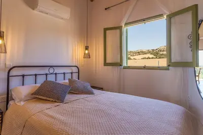 a bedroom with a bed with two pillows and a window at Eleonas Seaview Cottages in Alaminos