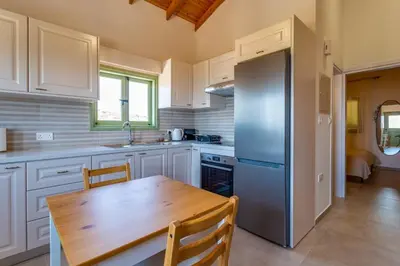 a kitchen with a wooden table and a refrigerator at Eleonas Seaview Cottages in Alaminos
