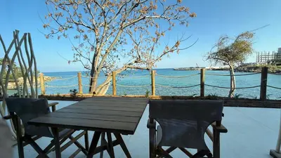 a wooden table and chairs sitting on a patio overlooking the water at Sirena Bay Beach House and Luxury Suites in Protaras