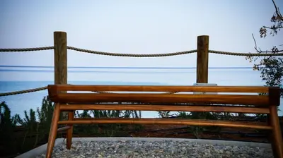 a wooden bench sitting on top of the ocean at Sirena Bay Beach House and Luxury Suites in Protaras