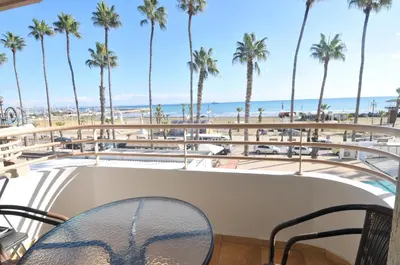 a view of the beach from the balcony of a resort with palm trees at Ithaki Phinikoudes Apartment No. 102 in Larnaka