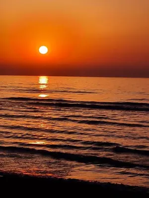 an orange sunset over the ocean with a beach at Ithaki Phinikoudes Apartment No. 102 in Larnaka