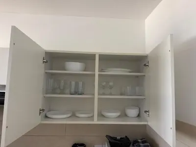 a white cabinet with white bowls and dishes in it at Ithaki Phinikoudes Apartment No. 202 in Larnaka