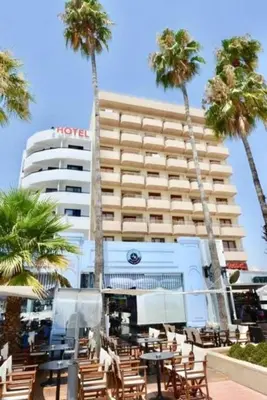 a hotel with chairs and palm trees in front of it at Ithaki Phinikoudes Apartment No. 204 in Larnaka