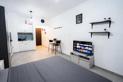 a living room with a television and a kitchen at Hubstay - Klea's Downtown City Apartment Suite in Larnaka
