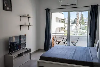 a bedroom with a bed and a tv and a balcony at Hubstay - Klea's Downtown City Apartment Suite in Larnaka
