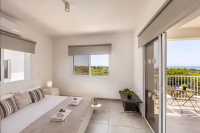 a white living room with a couch and a balcony at Ayia Napa Bay View Villa 5 in Ayia Napa