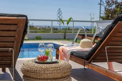 a patio with a table and glasses and a pool at Ayia Napa Bay View Villa 5 in Ayia Napa