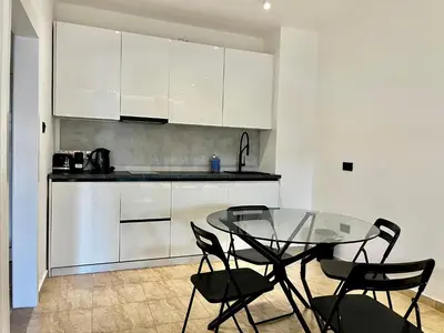 a kitchen with a glass table and black chairs at STAY Napa Velvet Apartment in Ayia Napa