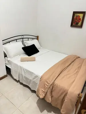 a bed with white sheets and a black pillow at Διαμέρισμα ισόγειο για ενοικίαση in Limassol