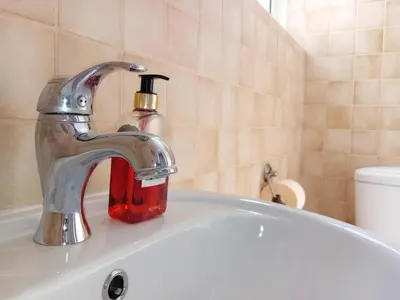 a bathroom sink with a faucet with a soap bottle at Green Door 3bdr flat City Centre in Nicosia