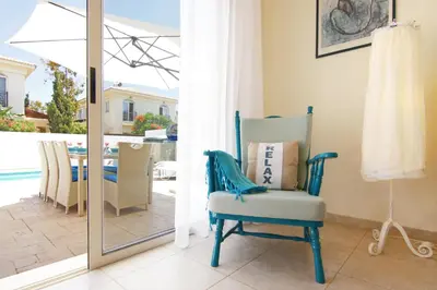 a blue chair sitting in a living room next to a sliding glass door at Sonja in Paralimni