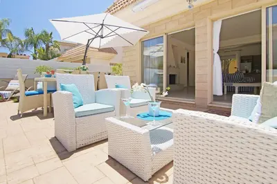 a patio with white wicker chairs and an umbrella at Sonja in Paralimni