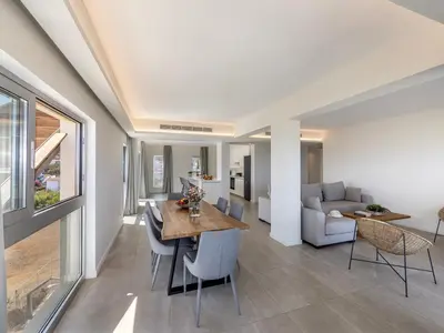 a dining room and living room with a table and chairs at Emerald Bay Sea-Front Penthouse in Protaras