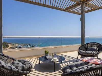 a patio with two chairs and a table on a balcony at Emerald Bay Sea-Front Penthouse in Protaras