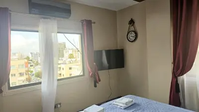 a bedroom with a window and a clock on the wall at STAY Van Gogh Apartment in Larnaka