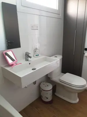 a white bathroom with a sink and a toilet at Studio In the Centre of the city in Ayia Napa