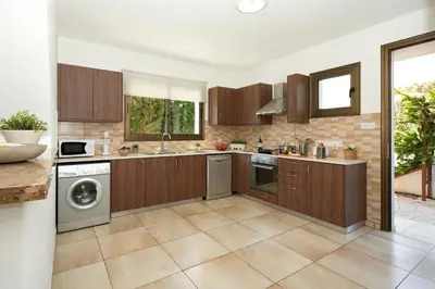 a kitchen with wooden cabinets and a washer and dryer at Villa Evia - Walking to Med Sea in Ayia Napa