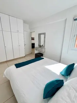 a bedroom with a large white bed with blue pillows at Georgiou 202 in Larnaka