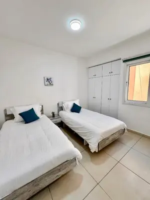 two beds in a white room with a window at Georgiou 202 in Larnaka