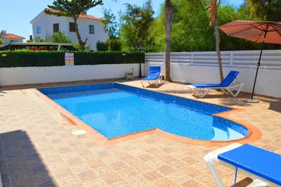 a swimming pool with two chairs and an umbrella at Ayia Napa Marina Luxury Villas - Pearl in Ayia Napa